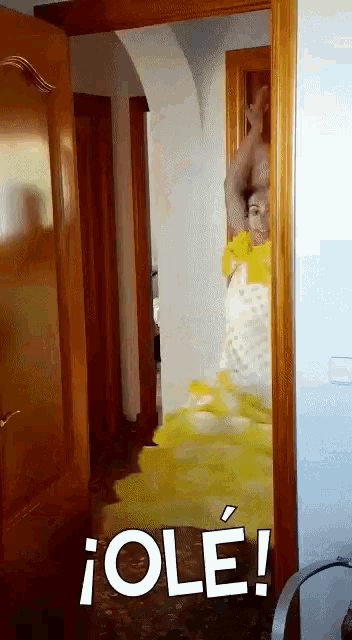a woman in a yellow dress is standing in a doorway with the words " ole " on the bottom right