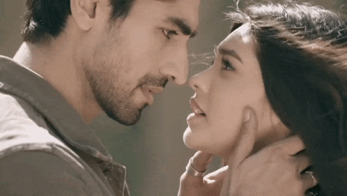 a man and woman are looking at each other and touching their faces .
